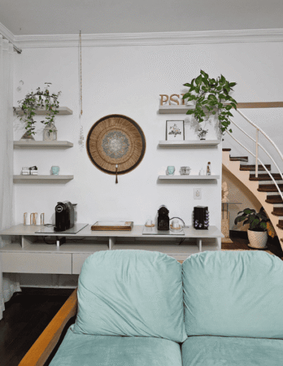 Balcão de recepção do Espaço Conheça-te com quadros, livros e plantas com cores claras que transmitem tranquilidade.